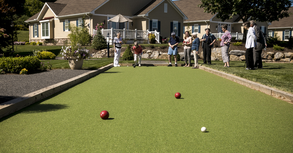 Senior citizen playing bocce ball on turf bocce court