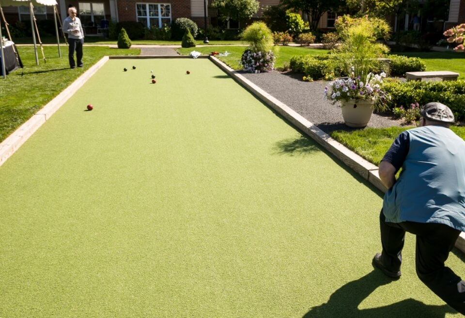 two people playing bocce competitively on a large, neat court