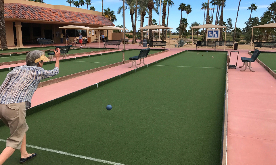 Senior woman playing bocce ball on a turf bocce court in a social area
