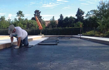 a worker installing subbase tiles for bocce court drainage