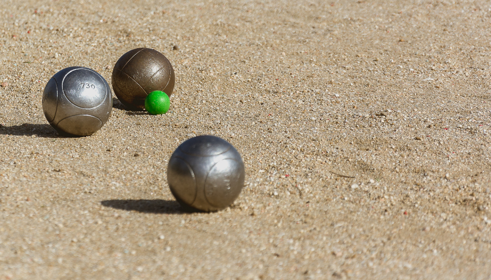 3 bocce balls on a tan sand/gravel bocce court