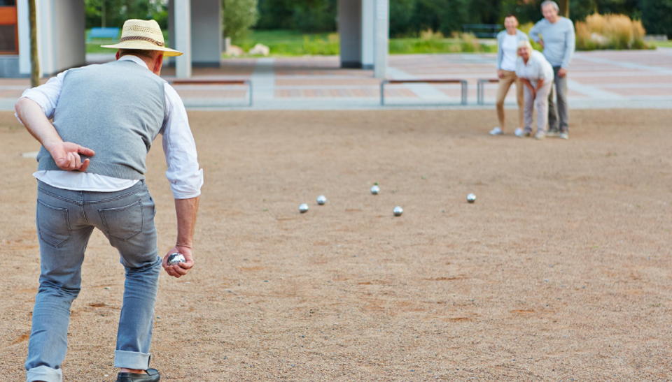 Senior citizen bocce ball player playing on a sand bocce court