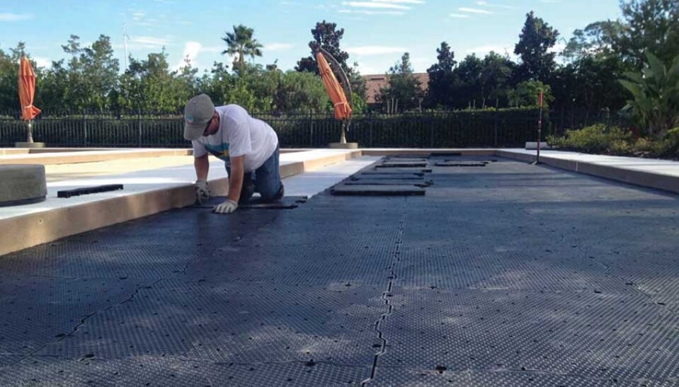 a worker installing Ultra Base panels for a flat, sound base to a bocce court