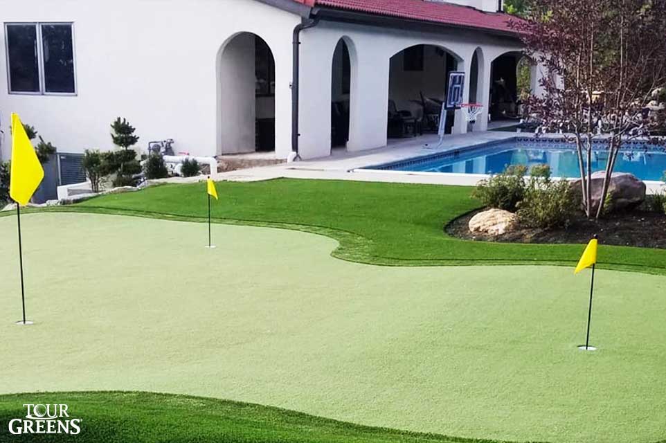Backyard short game putting green installed next to a pool