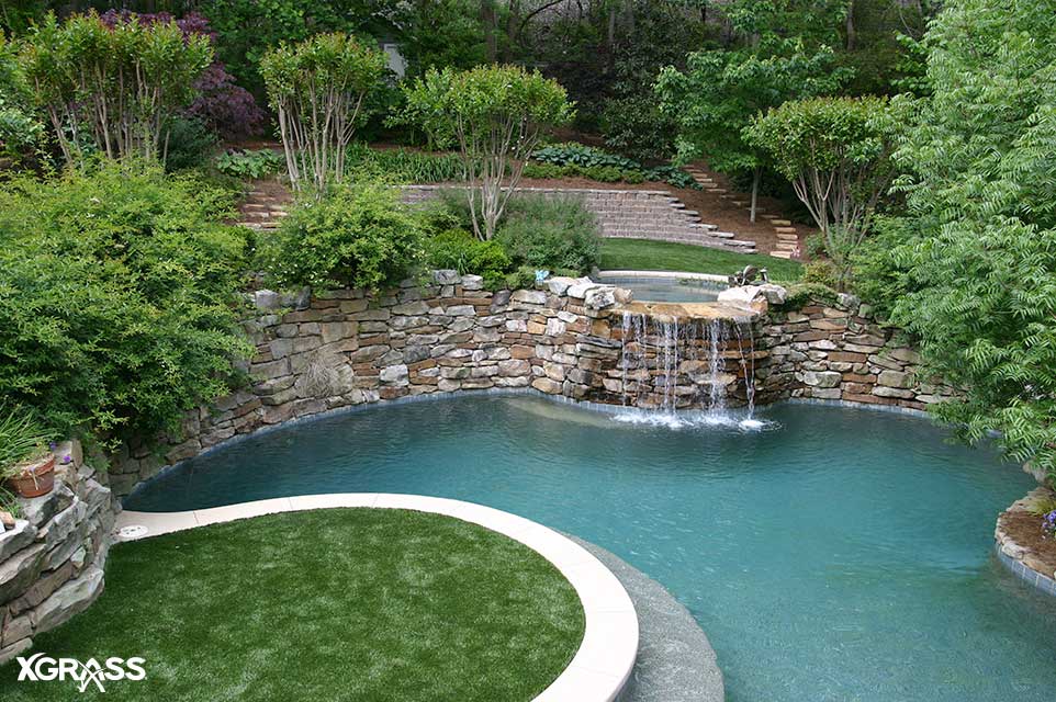 Artificial grass surrounds this backyard waterfall feature