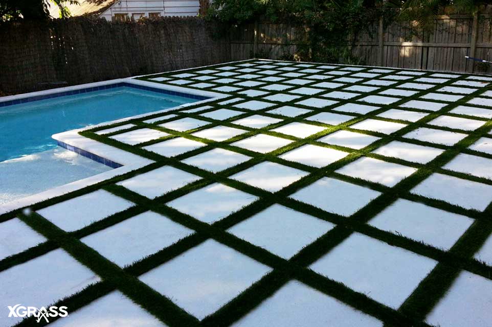 Backyard pool deck featuring concrete pavers and XGrass turf strips