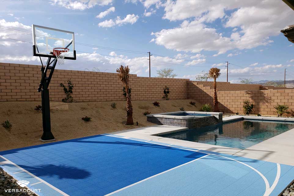 Backyard pool with a VersaCourt basketball court installed next to it