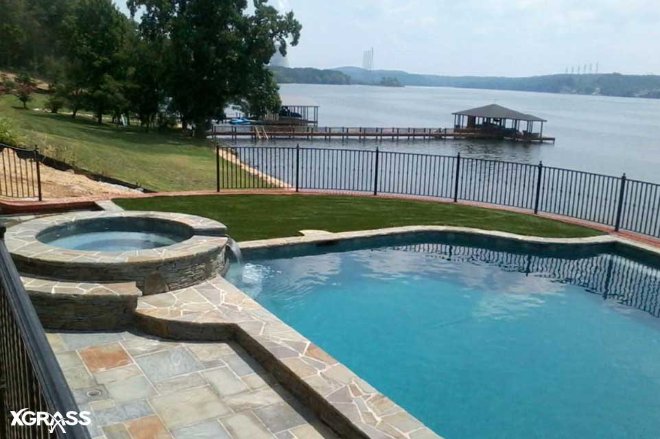 Synthetic turf installed next to backyard pool on a lakeside home