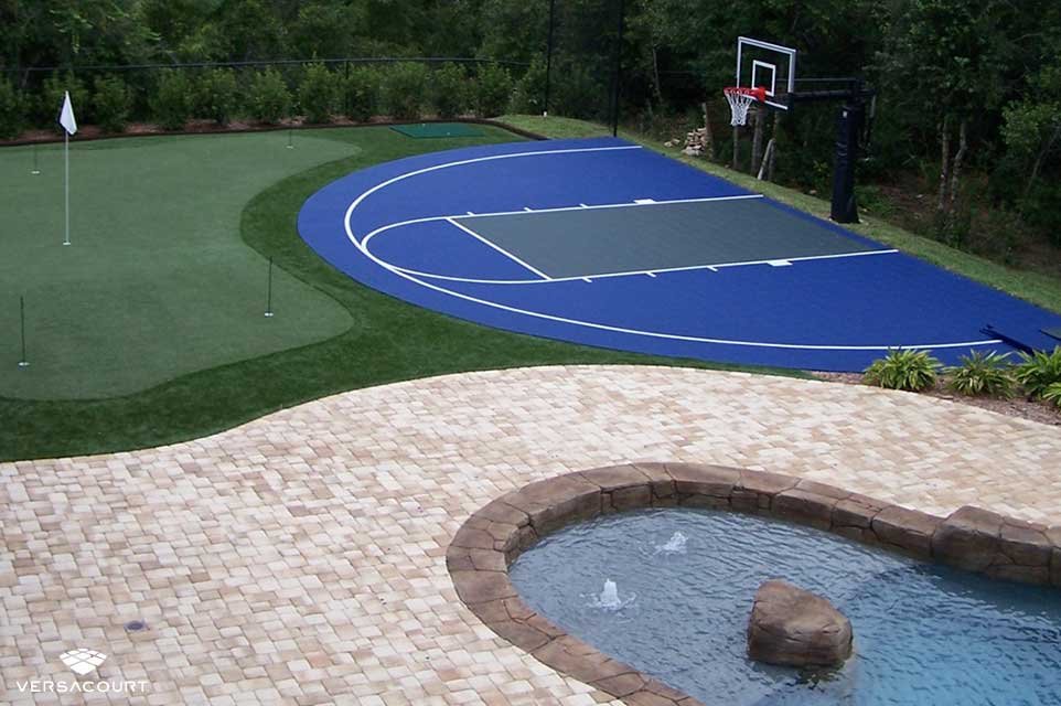 Putting green and half-court basketball court next to a backyard swimming pool