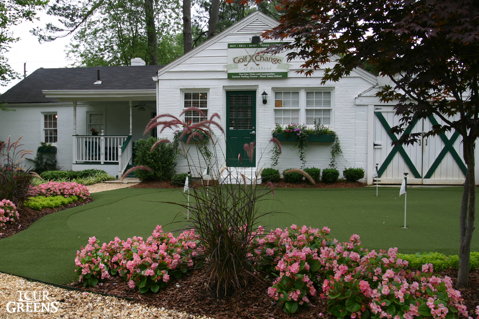 Small backyard putting green installed around a garden