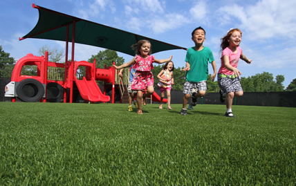 Kids happily running ontop of playground turf from XGrass